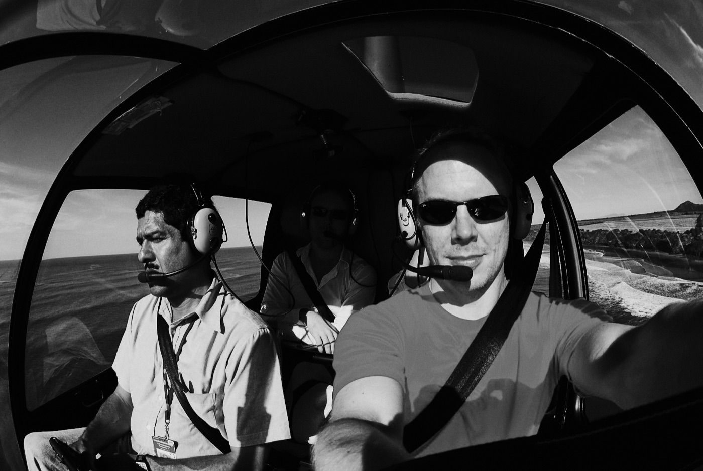 Svartvitt bild av Jonas Eriksson med kameran under ett fotouppdrag från helikopter i Nicaragua.